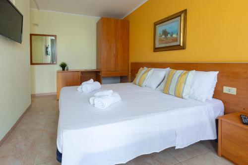 a bedroom with a large white bed with towels on it at Villa Vacanze Paradiso - Oasi di Tranquillità con Piscina e Giardino a 10 min dal mare in Neviano
