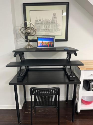 a black desk with a laptop on top of it at Bright, Private, Peaceful Suite with Retail Conveniences Steps Away in Toronto