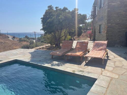 dos bancos sentados junto a una piscina en villa hibiscus with swimmimg pool see view few meters from beaches, en Koundouros