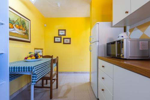a small kitchen with a table and a microwave at Villa Vacanze Paradiso - Oasi di Tranquillità con Piscina e Giardino a 10 min dal mare in Neviano