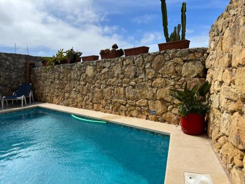 a swimming pool in front of a stone wall at 4 Bedroom Holiday Home with Private Pool & Views in Xewkija