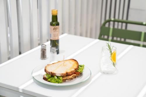 a sandwich on a white plate on a table with a bottle of wine at Vitaminas - Casa de Playa y Café in Punta del Este