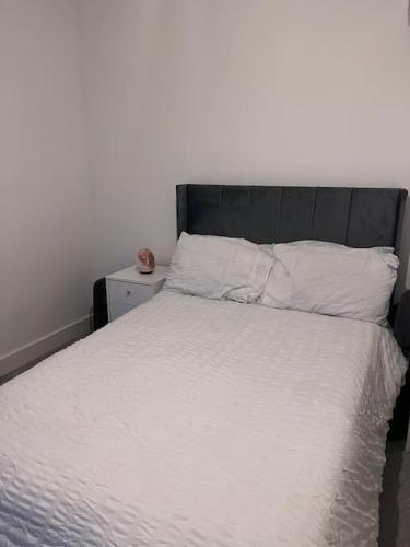 a bedroom with a white bed with a black headboard at Canterbury Penthouse: HUGE 2 bed ensuite + balcony in Canterbury