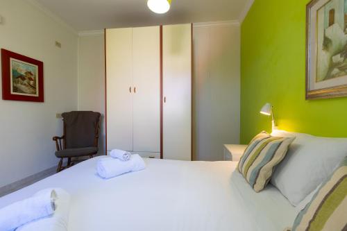 a bedroom with a white bed and a chair at Villa Vacanze Paradiso - Oasi di Tranquillità con Piscina e Giardino a 10 min dal mare in Neviano