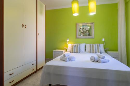 a green bedroom with a bed with towels on it at Villa Vacanze Paradiso - Oasi di Tranquillità con Piscina e Giardino a 10 min dal mare in Neviano
