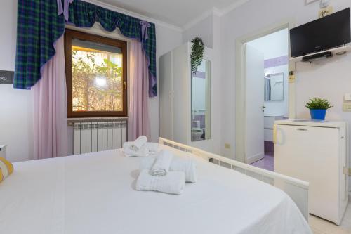 a bedroom with a white bed and a window at Villa Vacanze Paradiso - Oasi di Tranquillità con Piscina e Giardino a 10 min dal mare in Neviano