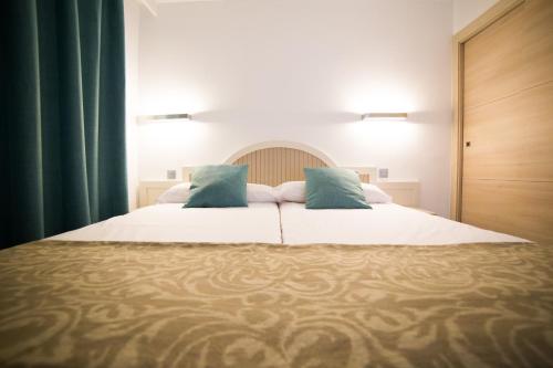 a bedroom with a large white bed with blue pillows at Cala D Or Apartamentos in Puerto Rico de Gran Canaria