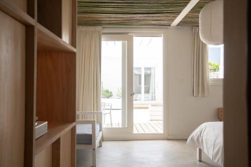 een slaapkamer met een bed en een glazen schuifdeur bij Vitaminas - Casa de Playa y Café in Punta del Este