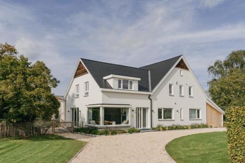una casa blanca con techo negro en MAM Haspengouw, en Sint-Truiden