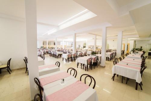 a restaurant with tables and chairs with pink and white tablecloths at Hotel Slaven in Selce
