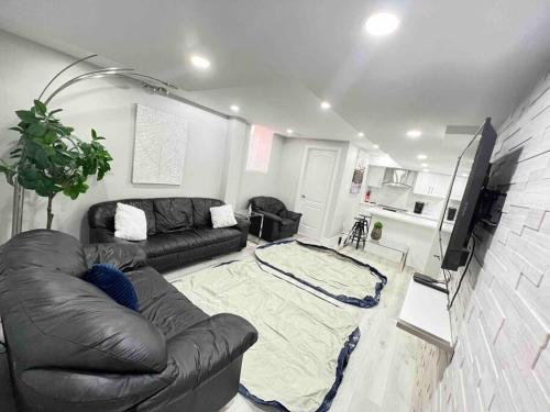 sala de estar con sofá de cuero y TV en Luxurious & upscale basement apartment, en Brampton