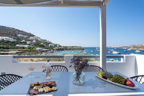 a table with a plate of food and a view of the ocean at BLUE WATERS MYKONOS in Ornos