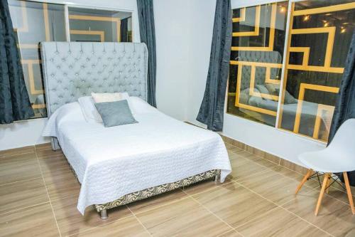 1 dormitorio con 1 cama, 1 silla y 1 ventana en Cabaña Familiar/La jagua Huila/Piscina y BBQ en Garzón