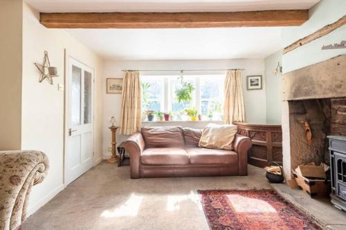 een woonkamer met een leren bank en een open haard bij Unique Willow Tree Bed in Quirky Home Stay Cottage, Near Holmfirth in Holmfirth