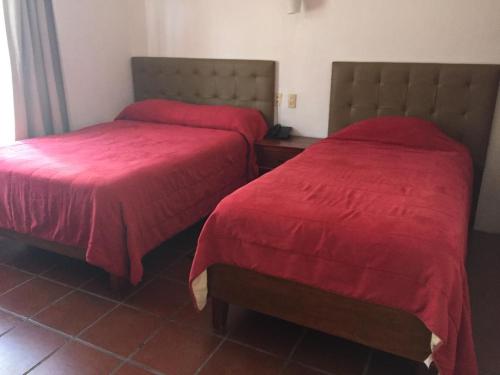 2 camas en una habitación de hotel con colchas rojas en posada el castellano, en Comitán de Domínguez