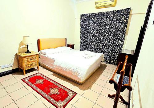 Ber-Santai at Marina Court في كوتا كينابالو: غرفة نوم بسرير وطاولة مع سجادة حمراء