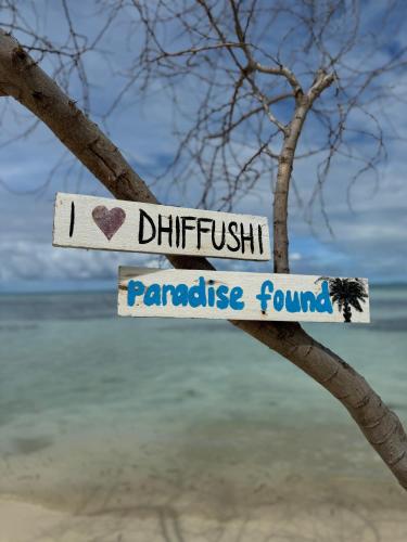 a sign on a tree in front of the beach at Noorani Retreat Dhiffushi in Dhiffushi