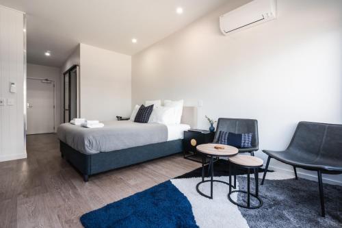een slaapkamer met een bed en 2 stoelen en een tafel bij Hanover Apartment No 1 in Dunedin