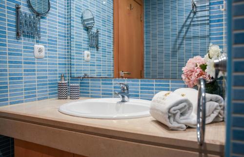 a bathroom sink with a towel and a vase of flowers at Apartamento Panoramico - By Dalma Portuguesa in Branqueira