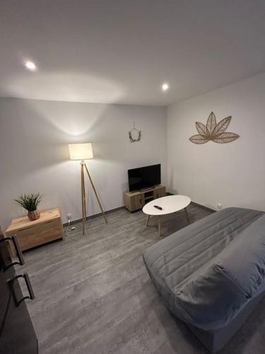 Schlafzimmer mit einem Bett, einem Tisch und einem TV in der Unterkunft Au Petit Faubourg in Roye