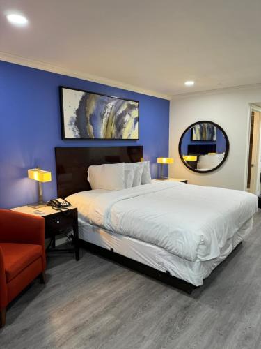 1 dormitorio con 1 cama grande y pared azul en Sands Motel, en Riverside