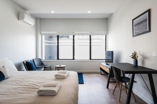 1 dormitorio con escritorio y 1 cama con toallas. en Hanover Apartment No 2 en Dunedin