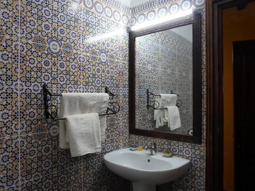 a bathroom with a sink and a mirror and towels at La Kasbah Elkhorbat Muxu Berbere in Asrir