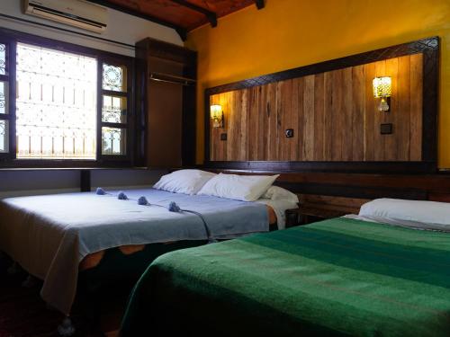 two beds in a room with two windows at La Kasbah Elkhorbat Muxu Berbere in Asrir