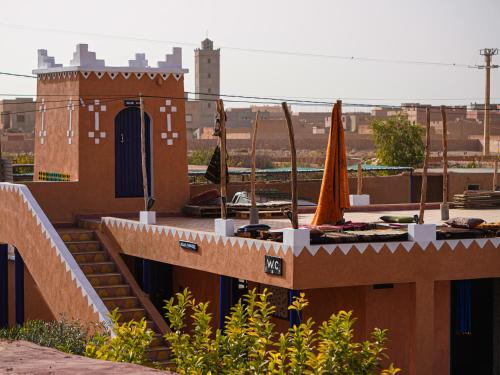 a building with a patio with an umbrella and stairs at La Kasbah Elkhorbat Muxu Berbere in Asrir