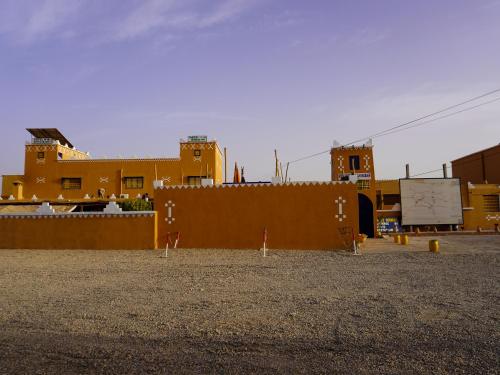 a group of yellow buildings in a parking lot at La Kasbah Elkhorbat Muxu Berbere in Asrir