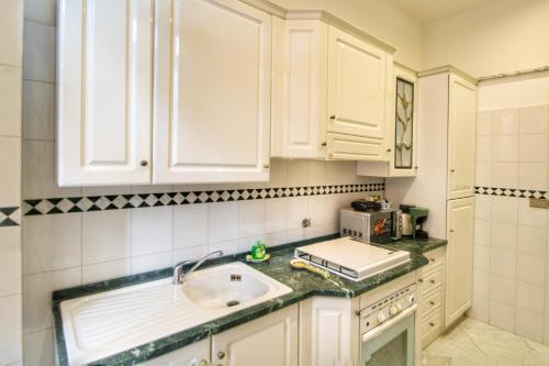 - une cuisine avec des placards blancs et un évier dans l'établissement Garibaldi Apartment in Trastevere By YourHost, à Rome