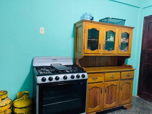 a kitchen with a stove and a wooden cabinet at Agradable casa de 4 habitaciones 2 baños cómodos in La Ceiba