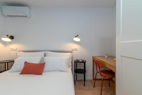a bedroom with a bed with white pillows and a desk at Jasna's Old Town Apartment in Trogir