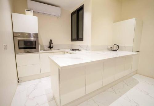 شقة انيقة وفاخرة بحي العليا Elegant and luxurious apartment Al-Olaya في الرياض: مطبخ أبيض مع دواليب بيضاء وميكرويف