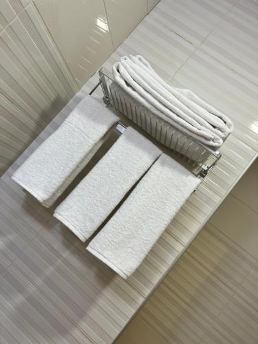 Soulmate Hotel Erbil في أربيل: ثلاث مناشف بيضاء على رف في حمام