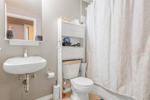 a bathroom with a white toilet and a sink at Chic 2-Bedroom Apt With Arcade in Edmonton