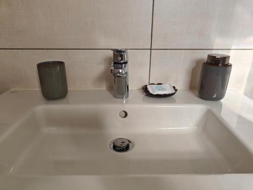a white sink with two cups on top of it at Orchidea Flat in Tripoli