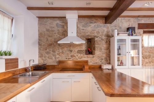 a kitchen with white cabinets and a stone wall at Casa vacacional Estudio 12 con encanto especial in Santander