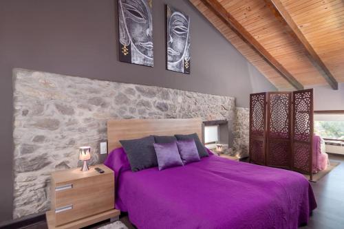 a bedroom with a purple bed and a stone wall at Casa vacacional Estudio 12 con encanto especial in Santander