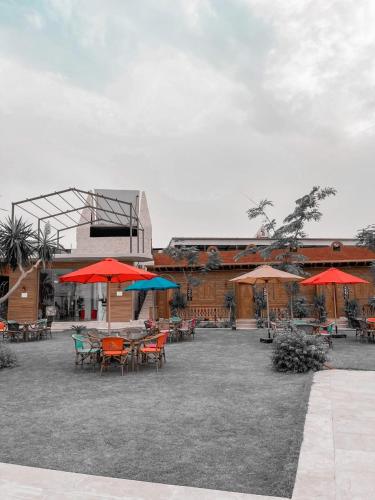 a patio with tables and umbrellas in front of a building at Tunis Pyramids Hotel - فندق اهرامات تونس in Tunis