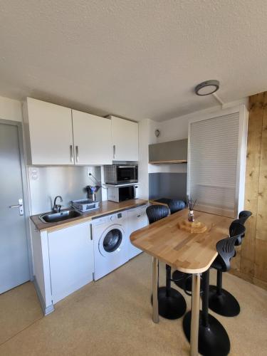 uma cozinha com uma mesa e uma máquina de lavar e secar roupa em Appartement avec vue sur montagnes + garage em Font Romeu Odeillo Via