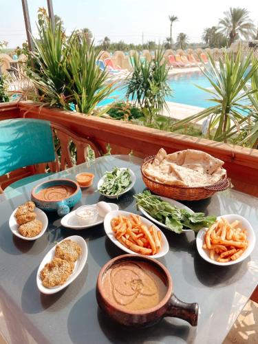 a table with plates of food on a table near a pool at Tunis Pyramids Hotel - فندق اهرامات تونس in Tunis