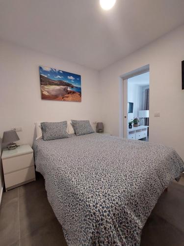 een slaapkamer met een bed en een schilderij aan de muur bij CASA ANTONIO Pasillo al Mar 40A in Costa Teguise
