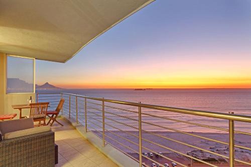 a balcony with a view of the ocean at sunset at Horizon Bay 1201 by HostAgents in Bloubergstrand