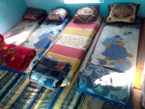 um grupo de quatro camas num quarto com almofadas em دارالضيافة git atlas em Megdaz