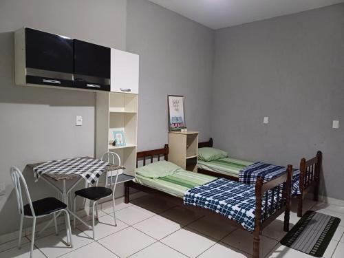 a room with two beds and a table and chairs at Flat Itavuvu in Sorocaba
