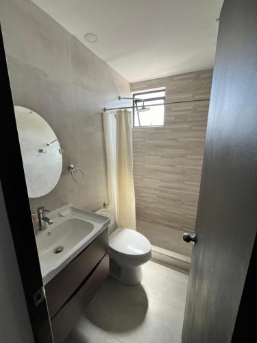 y baño con aseo, lavabo y espejo. en Hotel Santa María, en Iquique