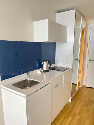 a white kitchen with a sink and a blue wall at Orbi city Sea view 5star in Batumi