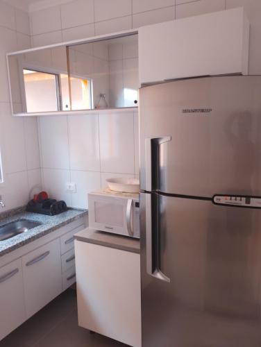 uma cozinha com um frigorífico e um micro-ondas em Cantinho do descanso em Bertioga