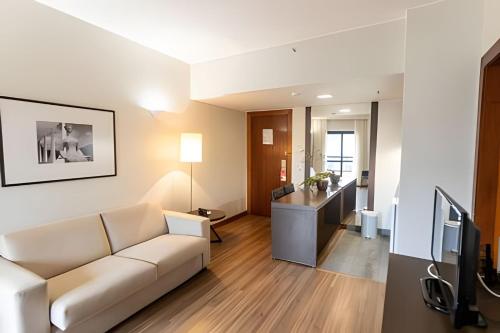 ein Wohnzimmer mit einem Sofa und einem TV in der Unterkunft Hotel Bonaparte Brasília - OZPED Flats in Brasilia